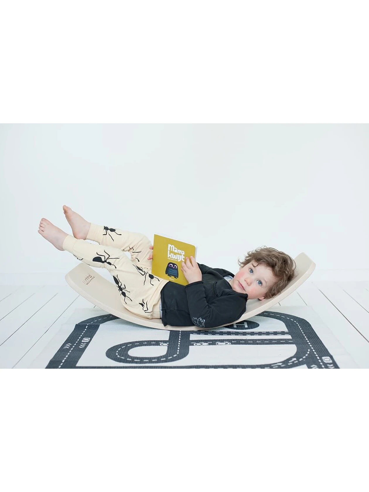 Dziecko na desce balansującej czyta książkę.