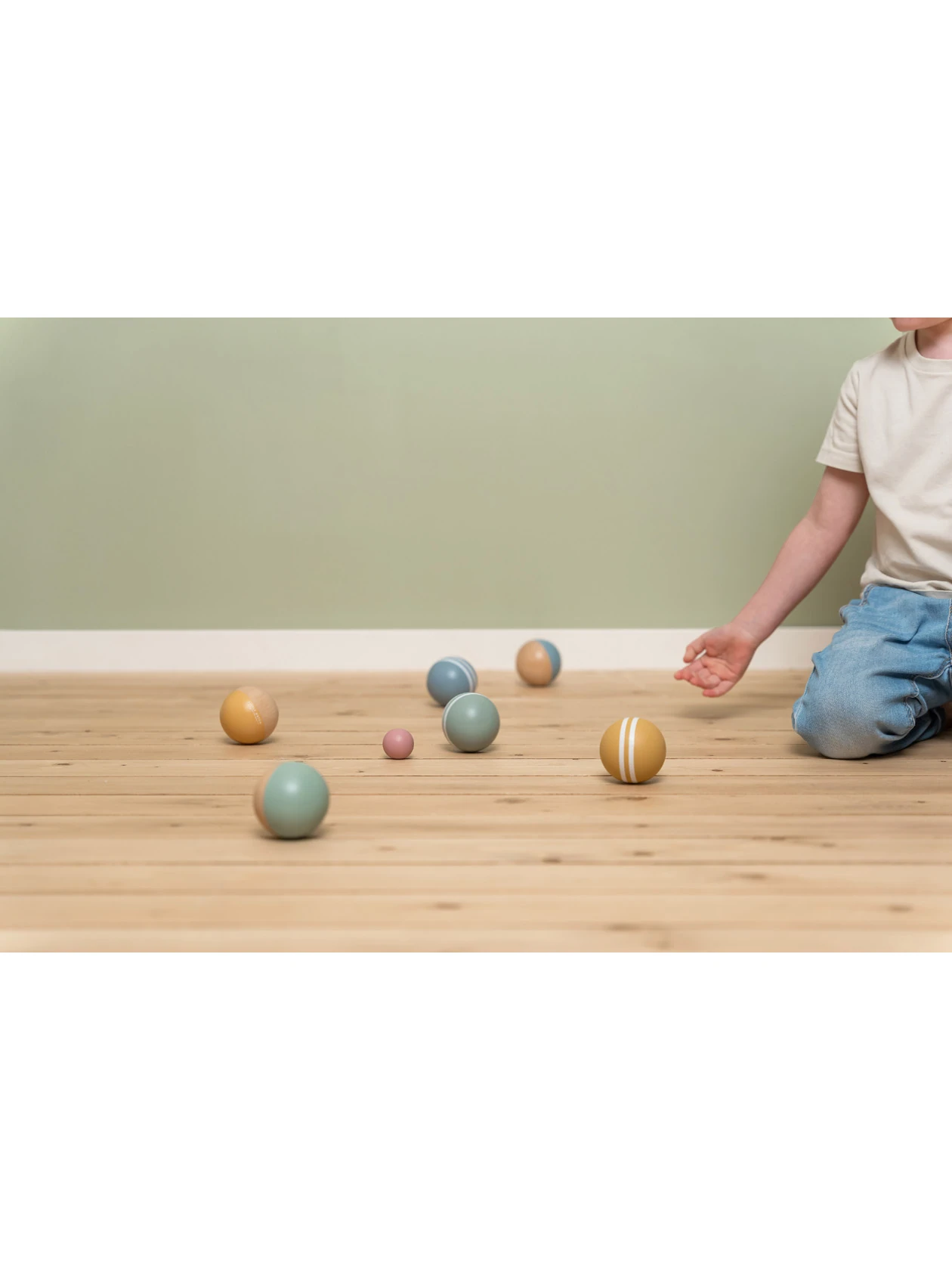 Chłopczyk turla piłki do gry Boules od Little Dutch na drewnianej podłodze w pokoju.