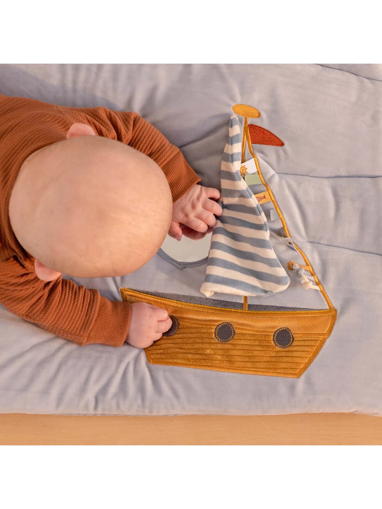 Maluszek bawi elementem w kształcie łódki na macie aktywizującej z serii Sailors Bay od Little Dutch.
