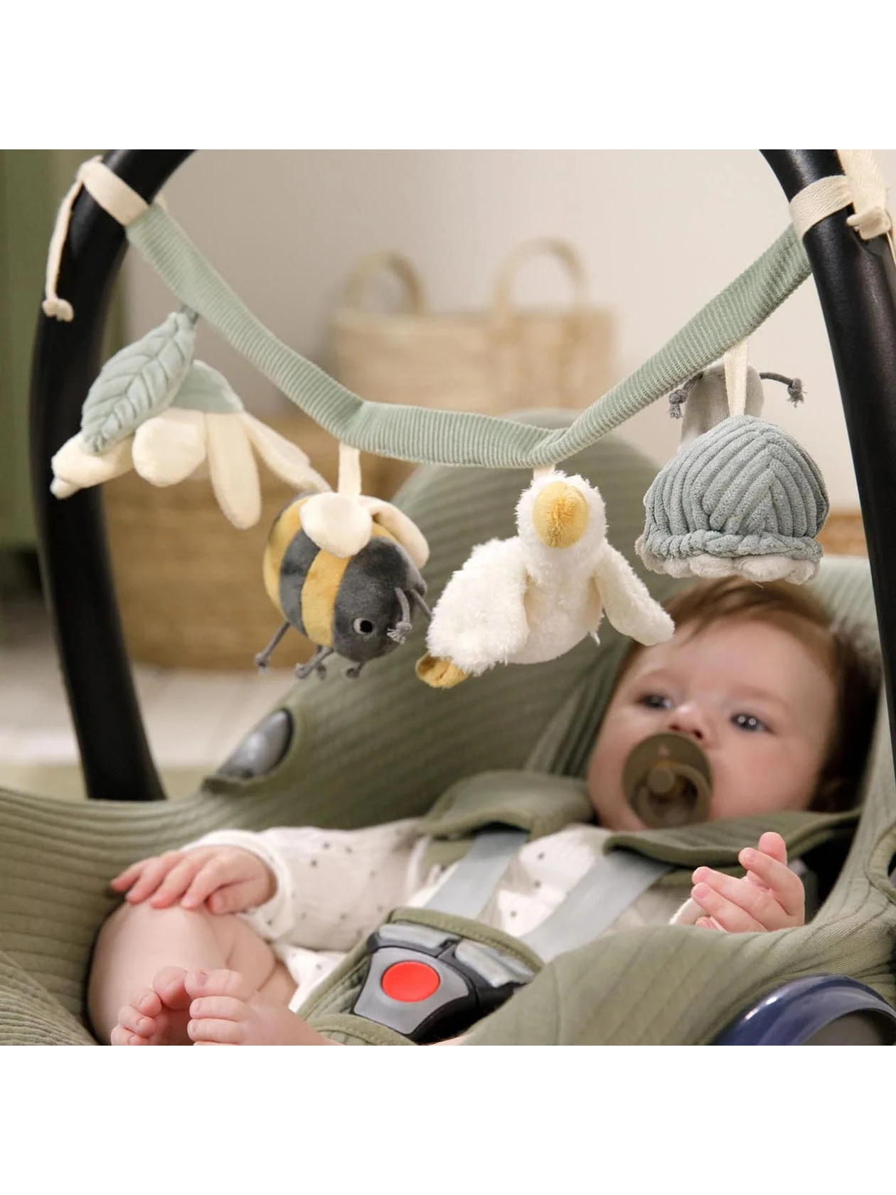 Dziecko w foteliku samochodowym z smoczkiem patrzące na zawieszkę sensoryczną z serii Little Goose od Little Dutch.
